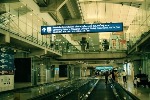 A moving walkway at Suvarnabhumi Airport in Bangkok, under an overhead sign for connecting flights to Chiang Mai