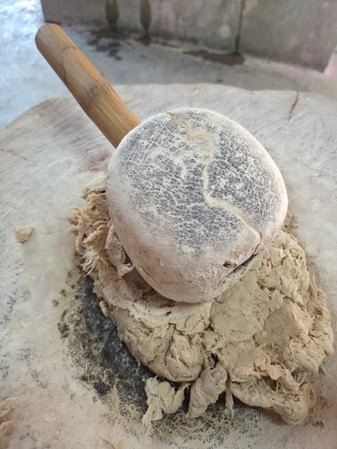 Un maillet de bois posé sur un tas de pâte à papier beige, sur un billot