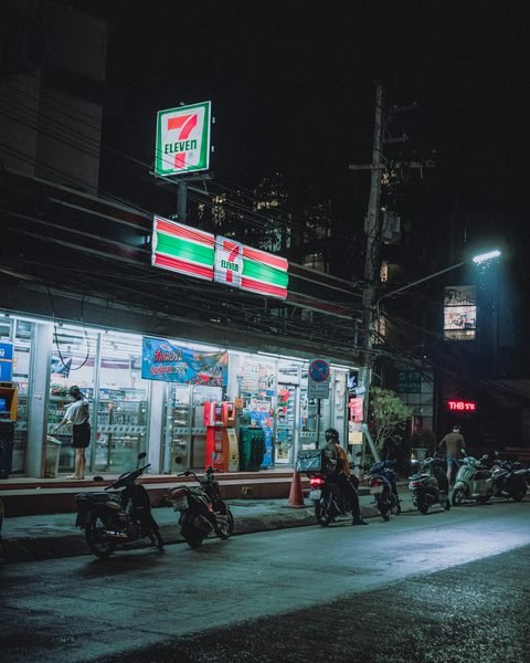 A brightly lit convenience store and parked motorbikes on a street at night