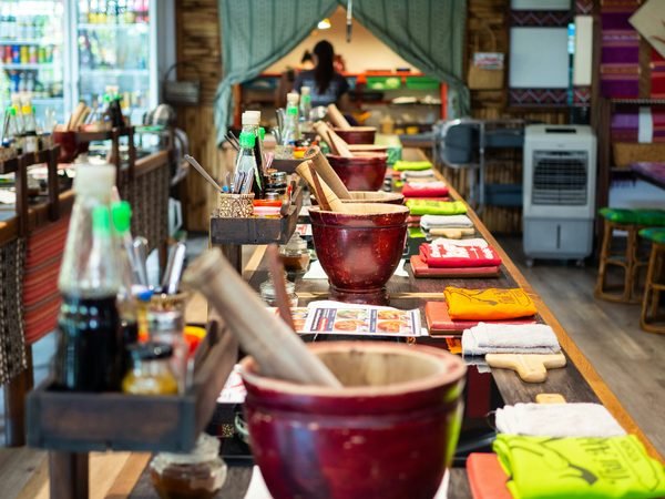 A row of cooking stations along a counter, stone mortars, prepared ingredients and sauce bottles ready