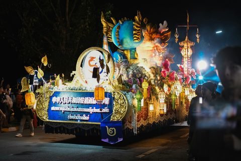 An illuminated parade float moving through the crowd at night