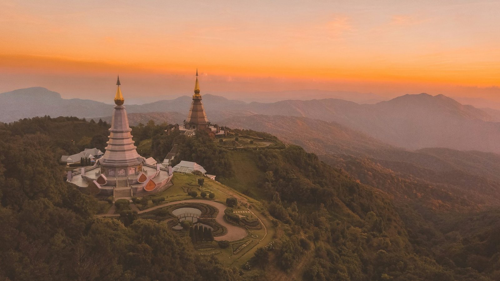 The twin royal pagodas of Doi Inthanon on their ridge at sunset, ranges of mountains fading behind
