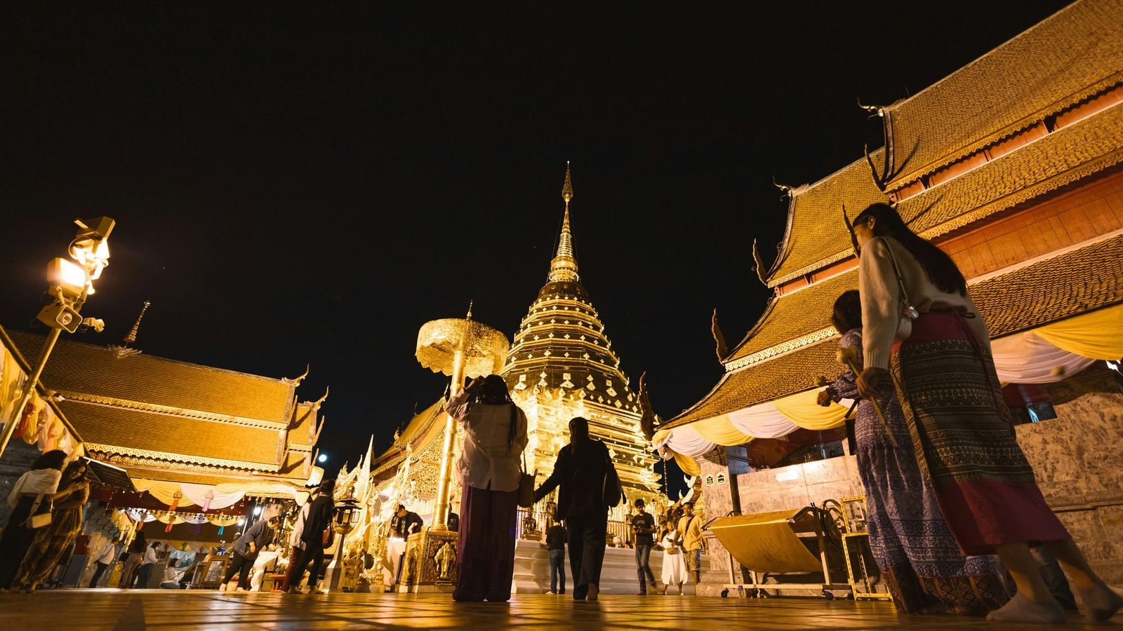 Visitors on the upper terrace of Wat Phra That Doi Suthep after dark, around the gilded chedi