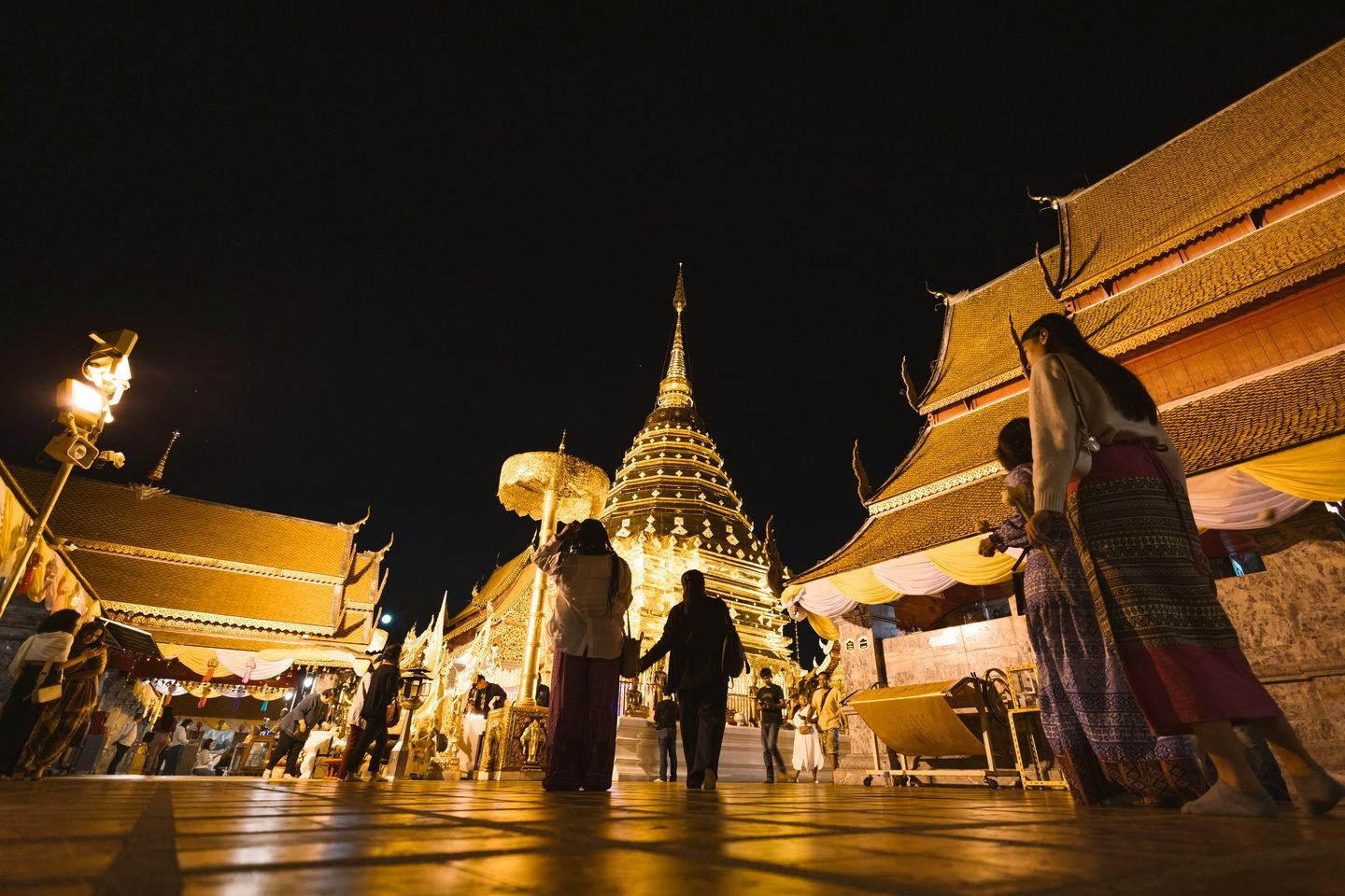 Visitors on the upper terrace of Wat Phra That Doi Suthep after dark, around the gilded chedi