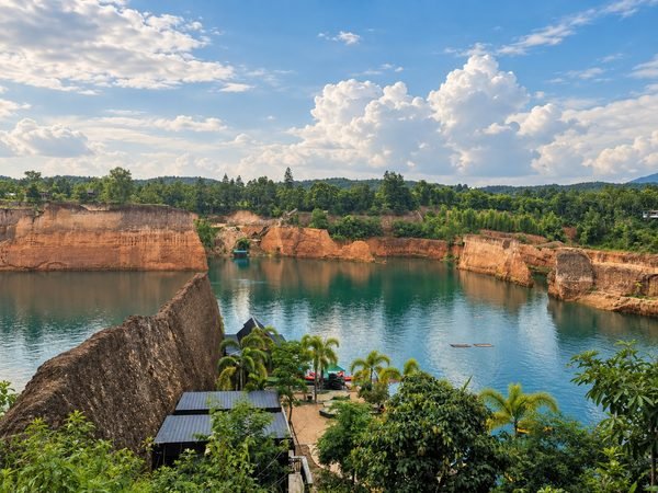 The Grand Canyon lake seen from the rim, green water between ochre quarry walls with wooded hills behind