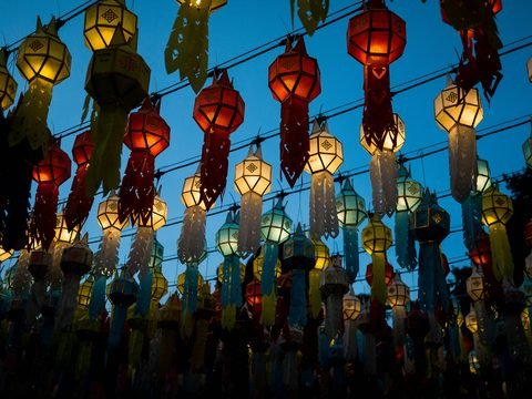 Des rangées de lanternes suspendues en papier, allumées, beaucoup à huit pans et à longues franges, sous un ciel bleu du soir