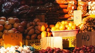 A northern Thai market stall stacked with vegetables and herbs in baskets and crates