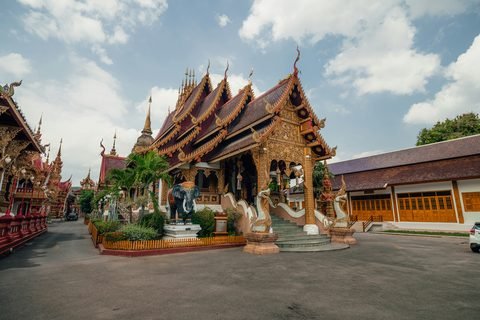 A Lanna wihan seen from the front, its roof falling in overlapping tiers above naga balustrades