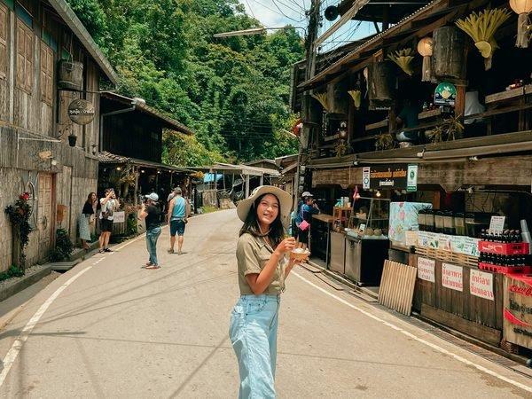The single street of Mae Kampong between wooden houses and stalls, forested hills closing the far end