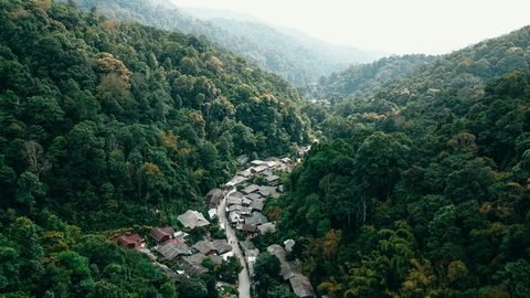 Mae Kampong from the air: the village's roofs along a road at the bottom of a forested valley