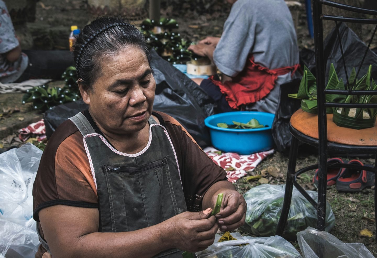 A vendor trimming fresh greens at a market table