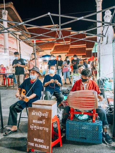 Musicians playing traditional instruments under a canopy at a night market