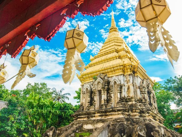 The gilded chedi of Wat Chiang Man, carried by carved stone elephants, seen under Lanna paper lanterns