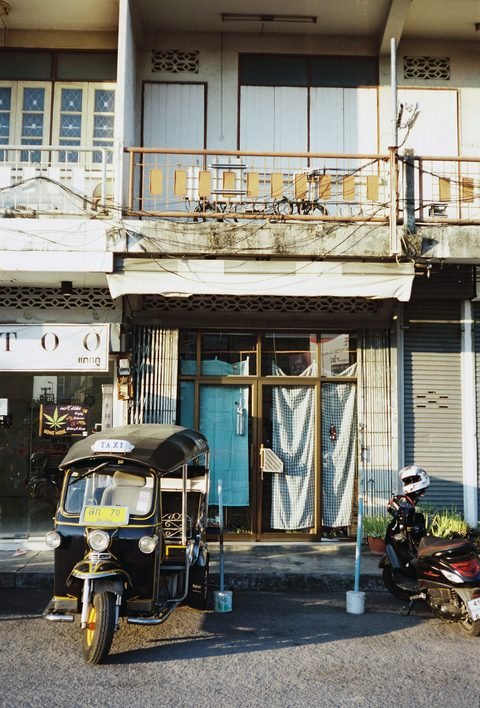 A tuk-tuk parked in front of an old two-storey shophouse
