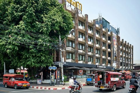 Red songthaews waiting at a crossroads under the trees