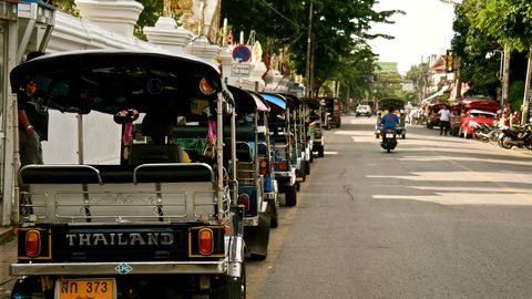 A line of tuk-tuks parked along a quiet street