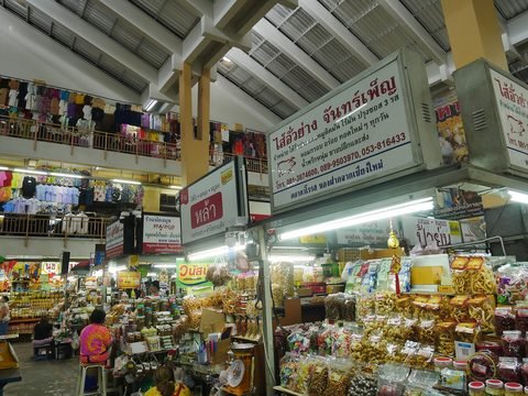 A ground-floor stall piled with bags of snacks under a large sai ua sign