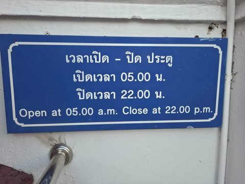 A blue sign in Thai and English: open at 05.00, close at 22.00