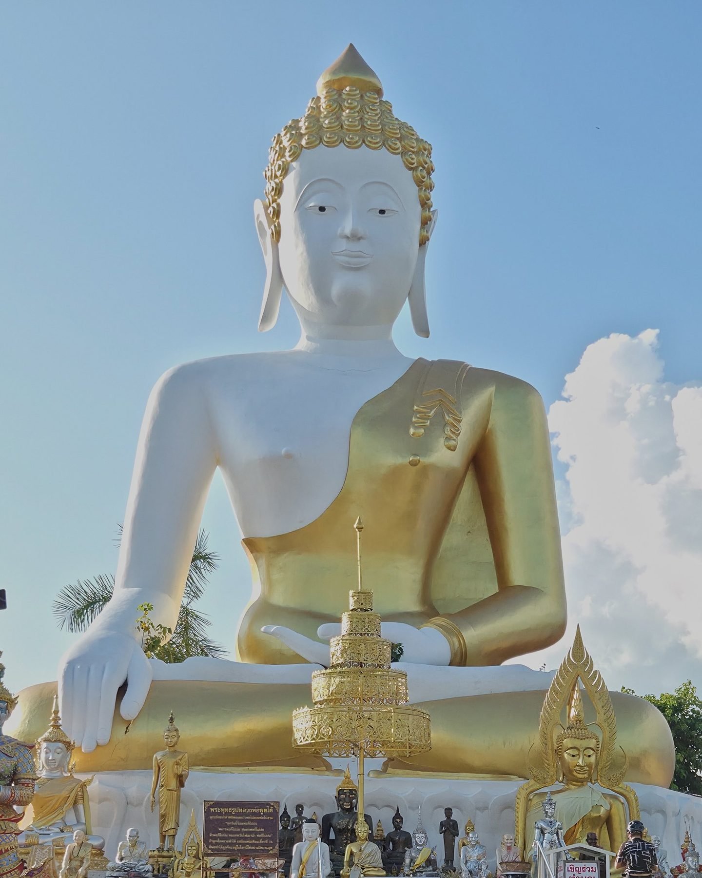 The face of the big white Buddha of Doi Kham, crowned with gilded curls, against a blue sky