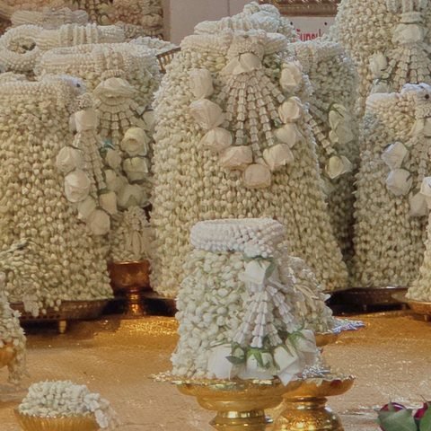 Close-up of jasmine cones: tight rows of threaded white buds, each crowned with a ring of flowers, standing on gilded bowls