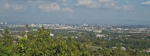 The plain of Chiang Mai seen from the summit: trees in the foreground, then the city spreading to the hills on the horizon