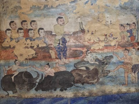 Mural detail: children lying on and riding water buffalo in a river while villagers watch from the bank