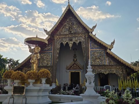 The east front of the Wihan Luang, its gilded gable above three doorways, with a gold statue under a parasol in front