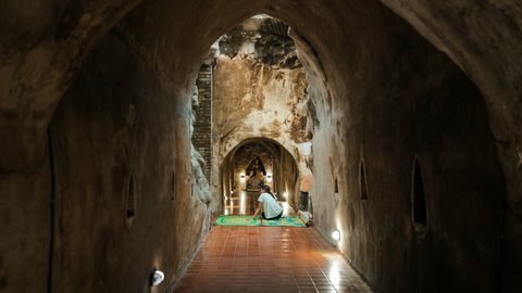 A brick tunnel at Wat Umong leading to a Buddha image at the far end