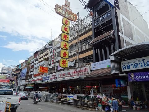 Wichayanon Road with tall gold-shop signs in Chinese and, at the right edge, the market's sign