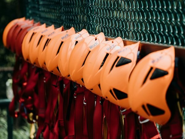 A rail of orange helmets above rows of red harnesses hanging ready at the platform